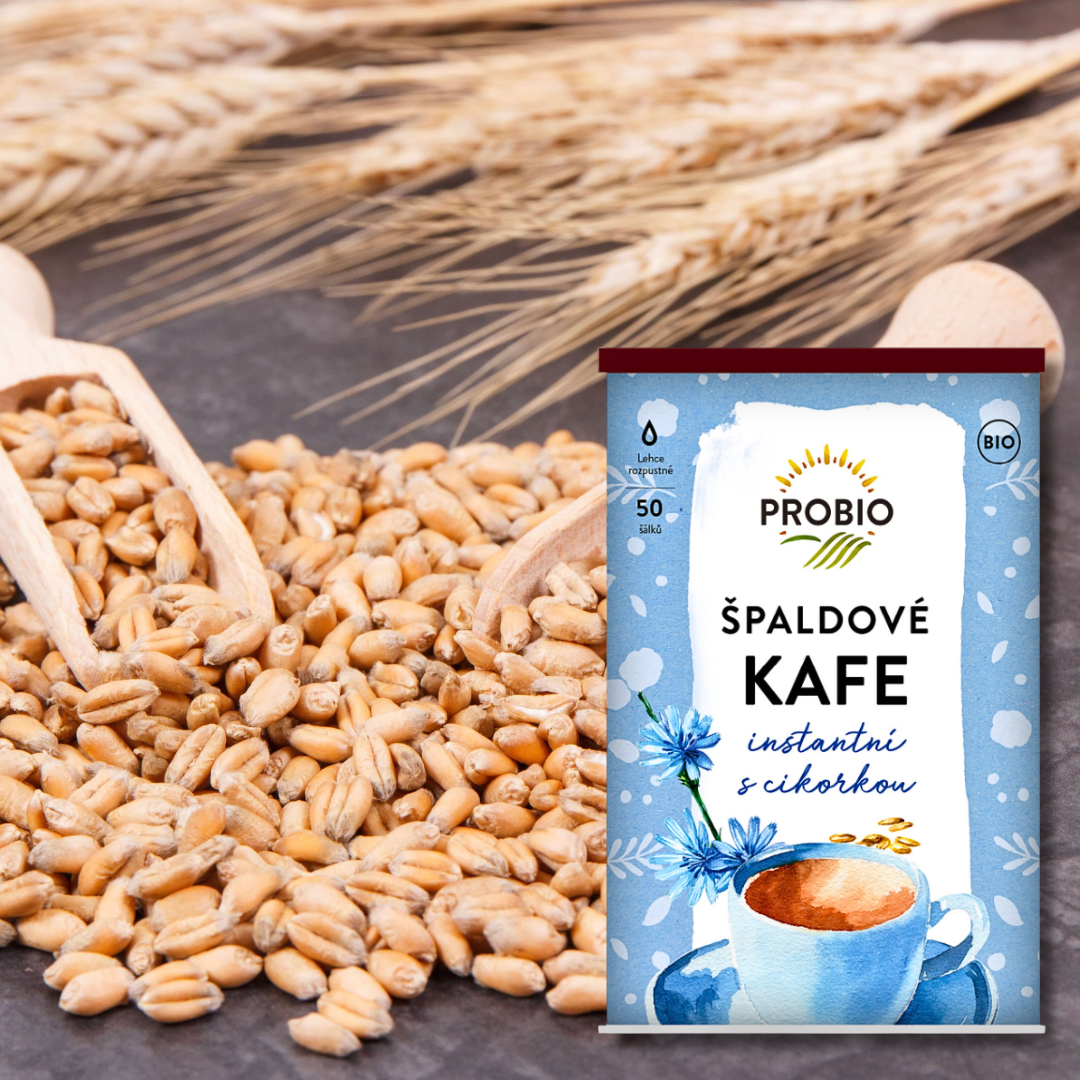 PROBIO “Špaldové kafe instantní s cikorkou” package standing next to a scoop and pile of spelt grains, with dried wheat ears in the background.